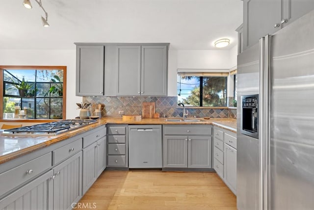 kitchen with sink, gray cabinets, decorative backsplash, and stainless steel appliances