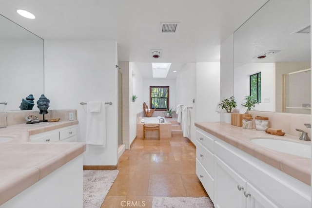 bathroom with vanity, a skylight, separate shower and tub, and tile patterned flooring