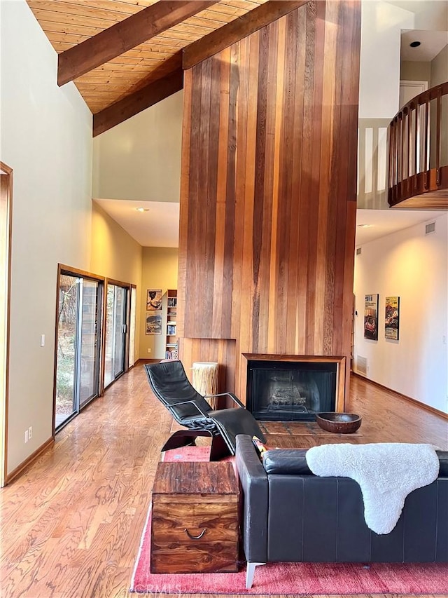 living room featuring wooden ceiling, beam ceiling, high vaulted ceiling, and a large fireplace