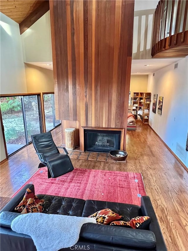 living room featuring beam ceiling, wooden ceiling, hardwood / wood-style floors, high vaulted ceiling, and wood walls