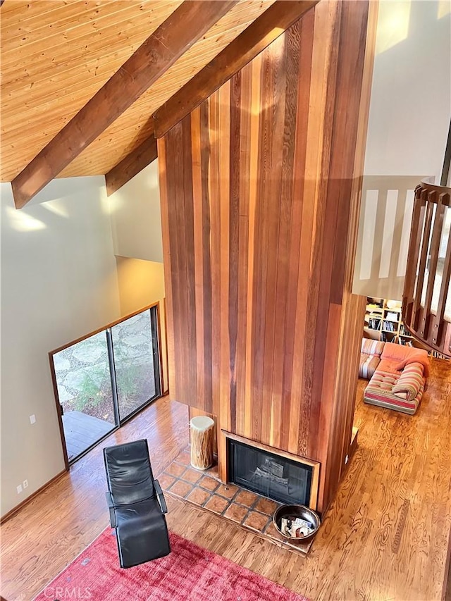 interior space with light hardwood / wood-style floors, wood walls, wood ceiling, and vaulted ceiling with beams