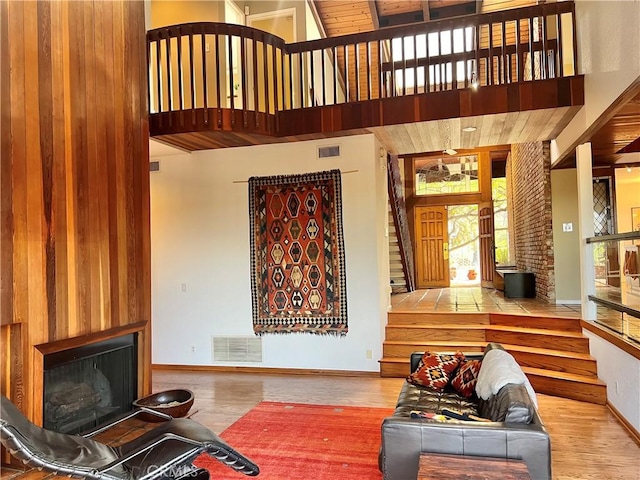 living room with a towering ceiling, wood-type flooring, and a fireplace