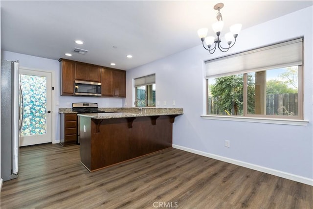 kitchen with plenty of natural light, dark hardwood / wood-style flooring, kitchen peninsula, and appliances with stainless steel finishes