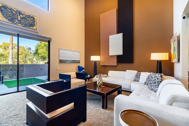 living room featuring carpet flooring, plenty of natural light, and a towering ceiling