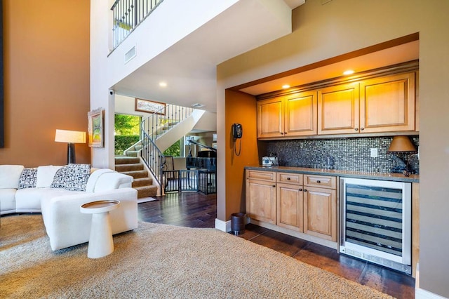 bar with decorative backsplash, a towering ceiling, wine cooler, and dark wood-type flooring