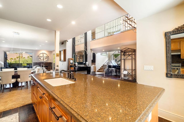 kitchen with stone counters, stainless steel range, sink, dark wood-type flooring, and ventilation hood