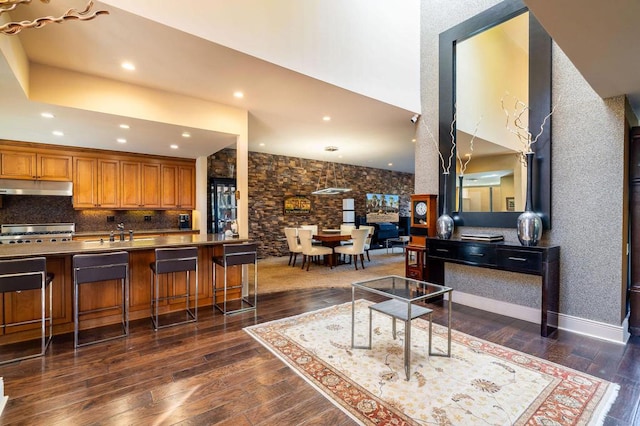 kitchen with stainless steel range, a towering ceiling, dark wood-type flooring, and a breakfast bar area