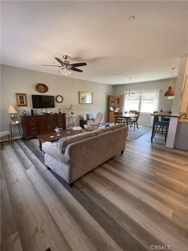 living room featuring ceiling fan with notable chandelier and dark hardwood / wood-style floors