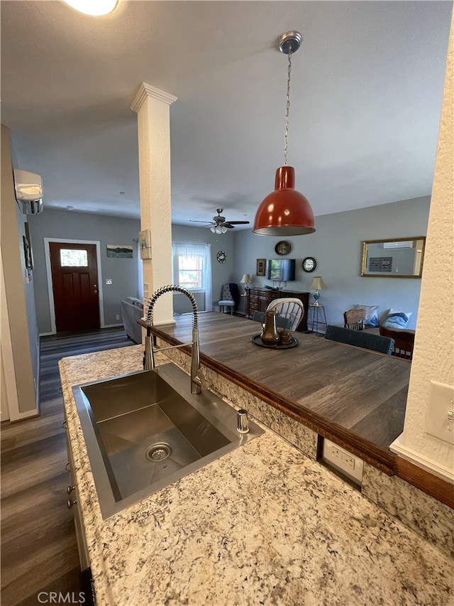 kitchen with ceiling fan, sink, wood counters, an AC wall unit, and decorative light fixtures