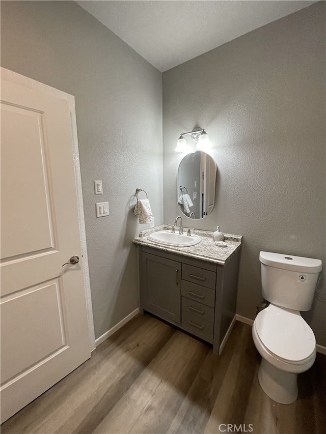 bathroom with hardwood / wood-style floors, vanity, and toilet