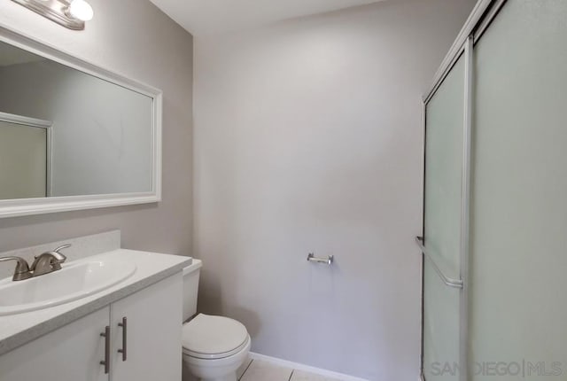 bathroom with tile patterned flooring, vanity, a shower with shower door, and toilet