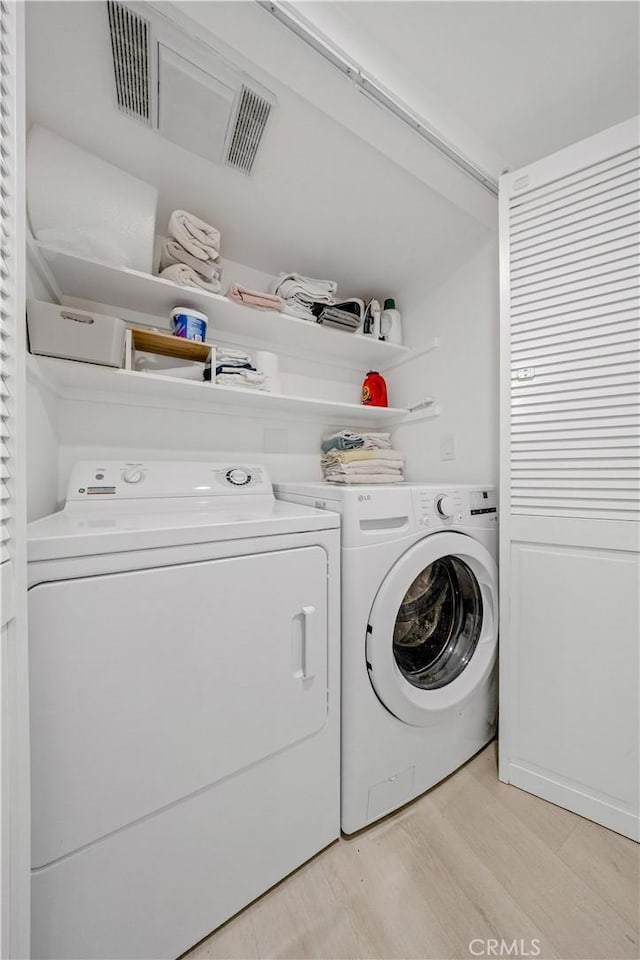 laundry area featuring separate washer and dryer and light hardwood / wood-style flooring