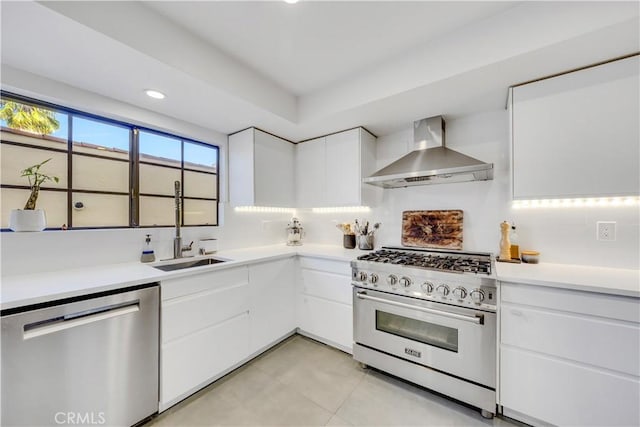 kitchen with backsplash, wall chimney exhaust hood, stainless steel appliances, sink, and white cabinetry