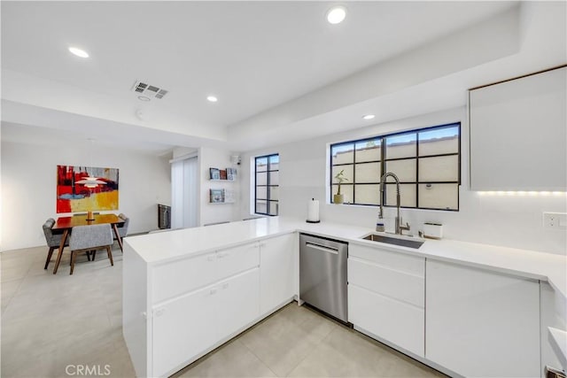 kitchen featuring a raised ceiling, kitchen peninsula, sink, stainless steel dishwasher, and white cabinetry