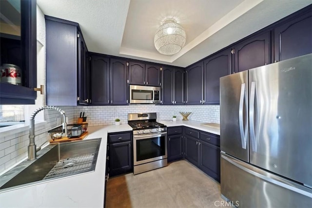 kitchen featuring decorative backsplash, stainless steel appliances, a tray ceiling, and sink