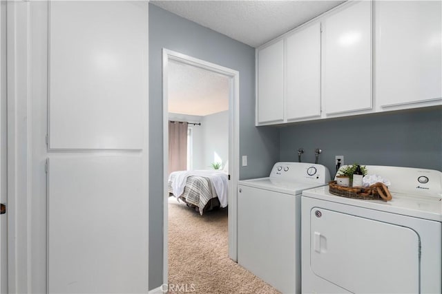 clothes washing area featuring cabinets, separate washer and dryer, a textured ceiling, and light carpet