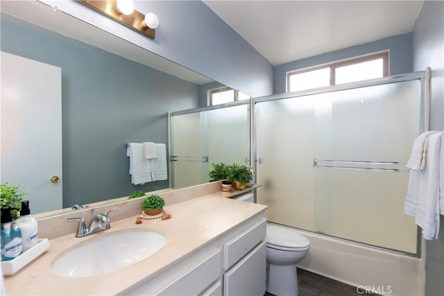 full bathroom with toilet, vanity, enclosed tub / shower combo, and hardwood / wood-style flooring