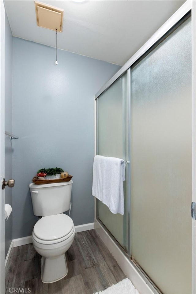 bathroom featuring toilet, wood-type flooring, and walk in shower