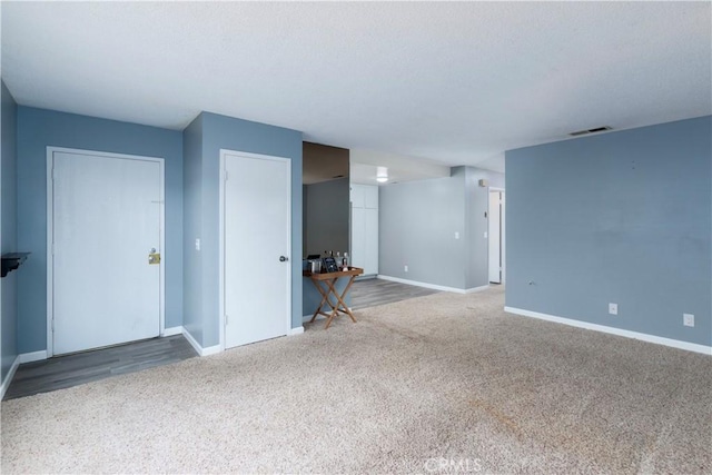 unfurnished living room featuring carpet and a textured ceiling