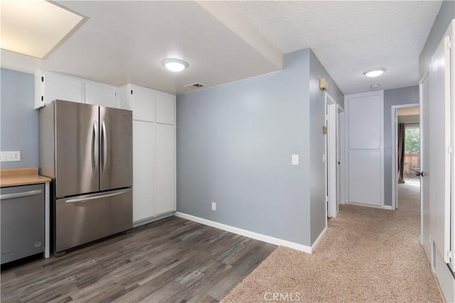 kitchen with white cabinets, dark hardwood / wood-style floors, a textured ceiling, and appliances with stainless steel finishes