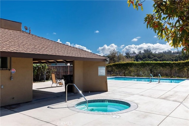 view of swimming pool featuring a patio and a hot tub