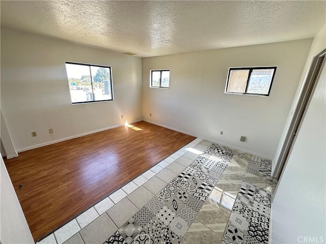 unfurnished room with plenty of natural light, light hardwood / wood-style floors, and a textured ceiling