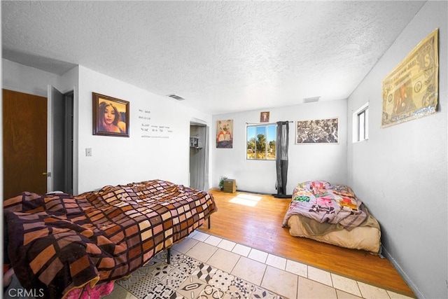 bedroom with a textured ceiling and light wood-type flooring