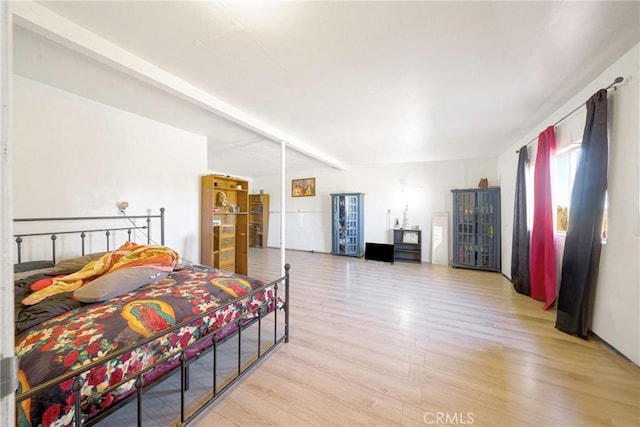 bedroom with beam ceiling and light wood-type flooring