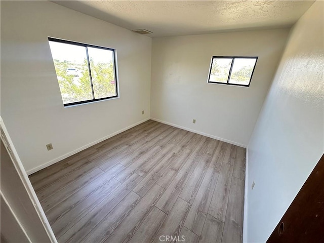 unfurnished room featuring a textured ceiling and light wood-type flooring