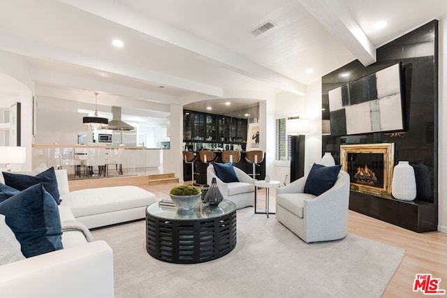 living room featuring beam ceiling and light hardwood / wood-style floors