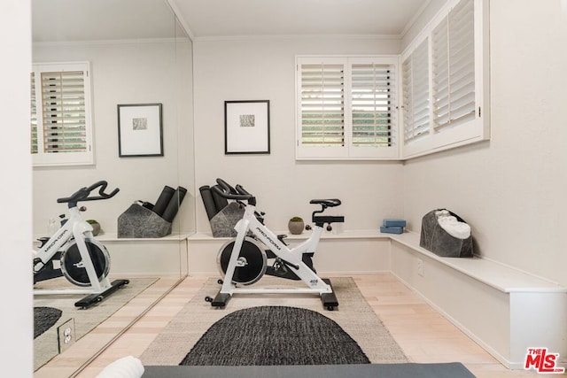 workout room featuring light wood-type flooring and crown molding