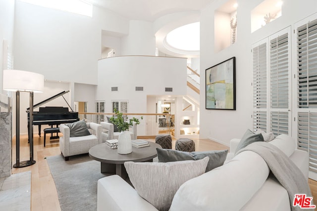 living room featuring a towering ceiling and light wood-type flooring