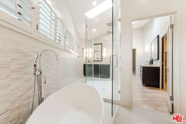 bathroom featuring lofted ceiling, vanity, tile patterned flooring, and shower with separate bathtub