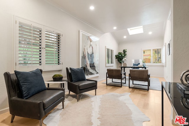 living area with light wood-type flooring, crown molding, and lofted ceiling with skylight