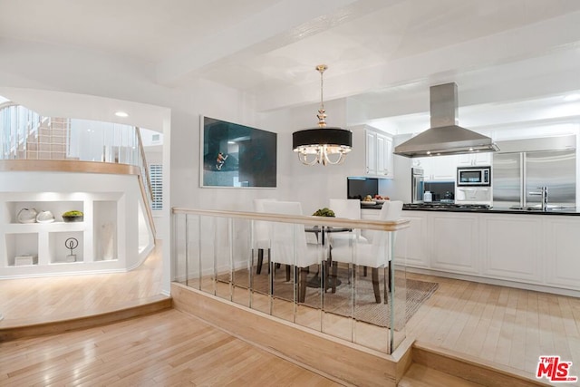 dining area featuring light hardwood / wood-style floors, sink, beam ceiling, and a notable chandelier