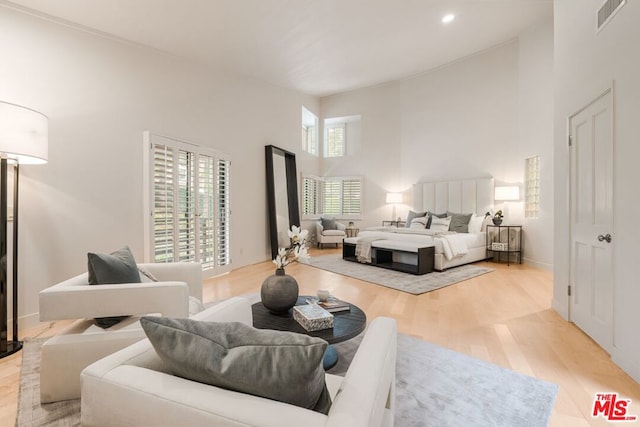 bedroom featuring light wood-type flooring and a towering ceiling