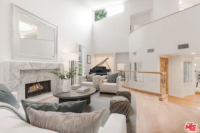 living room with a fireplace, a towering ceiling, and wood-type flooring