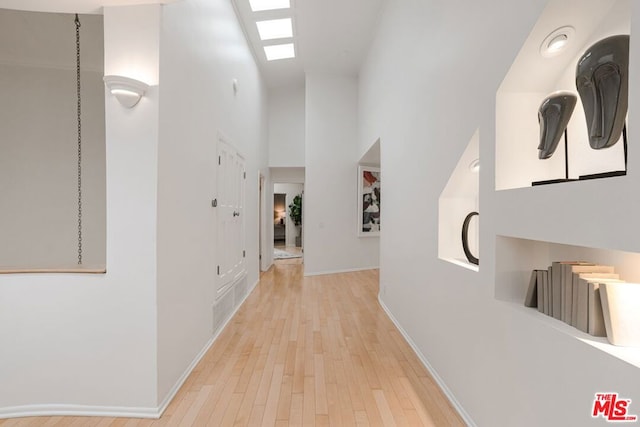 corridor with light wood-type flooring and a skylight