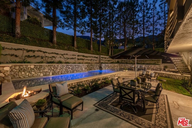 view of patio / terrace featuring a fenced in pool and a fire pit