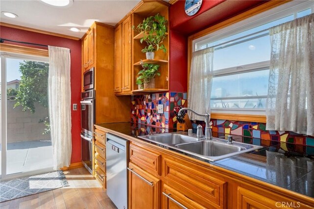 kitchen featuring backsplash, sink, stainless steel appliances, and light hardwood / wood-style flooring