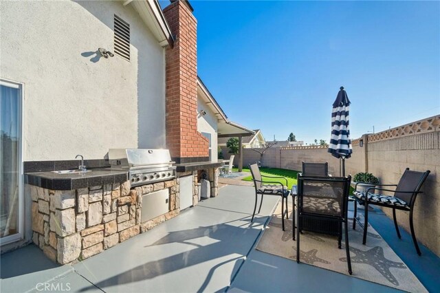 view of patio with grilling area, sink, and exterior kitchen