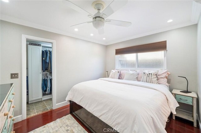 bedroom with a walk in closet, a closet, crown molding, and ceiling fan