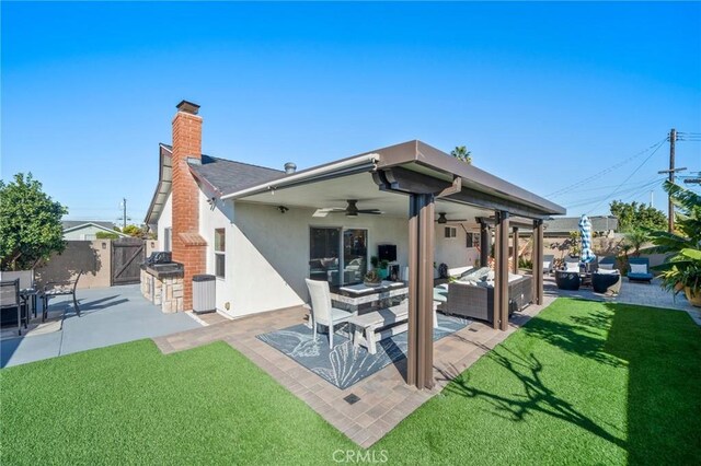 rear view of property featuring a lawn, ceiling fan, a patio area, and an outdoor hangout area