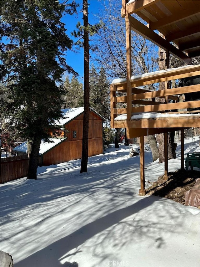 snowy yard featuring an outbuilding, fence, and a storage unit