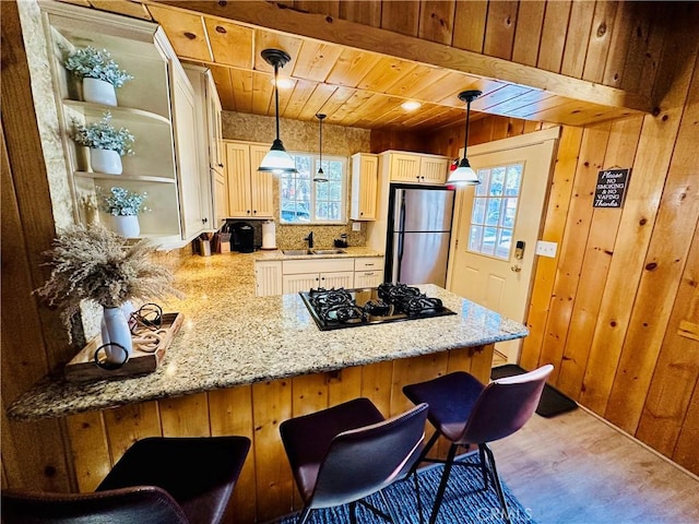 kitchen featuring kitchen peninsula, stainless steel refrigerator, hanging light fixtures, and a breakfast bar area