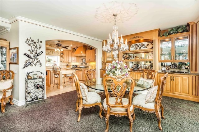 carpeted dining area featuring ceiling fan with notable chandelier and crown molding