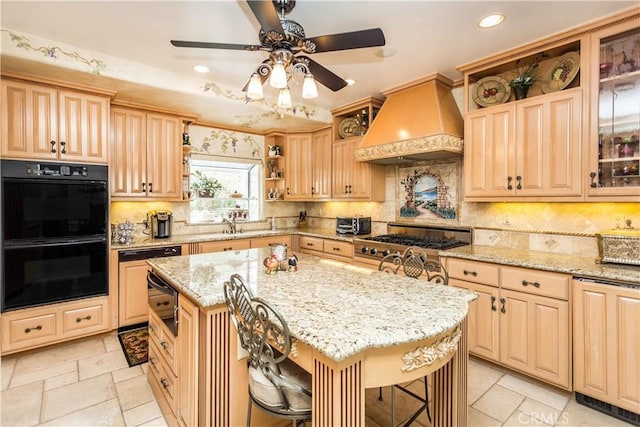 kitchen featuring light stone countertops, double oven, a breakfast bar, a kitchen island, and custom range hood