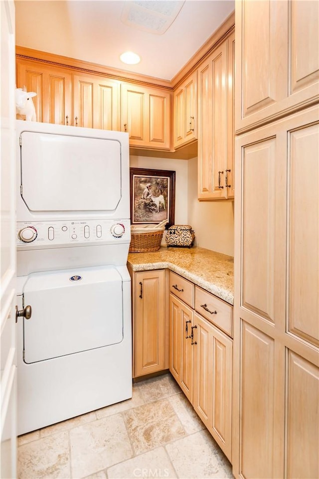 laundry room featuring stacked washer / drying machine and cabinets