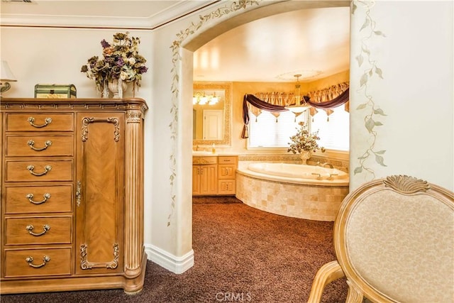 bathroom with vanity, ornamental molding, and tiled tub