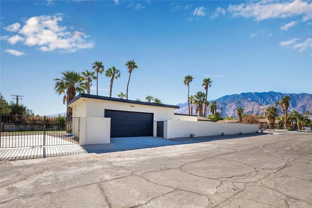 exterior space featuring a gate, a mountain view, stucco siding, and fence